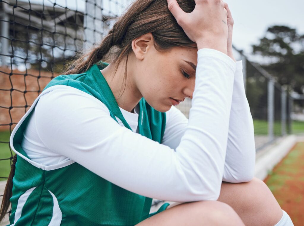 Frau sitzt traurig auf dem Boden Hormone und Energiehaushalt Herausforderungen für Sportlerinnen Research spt-education Red-s