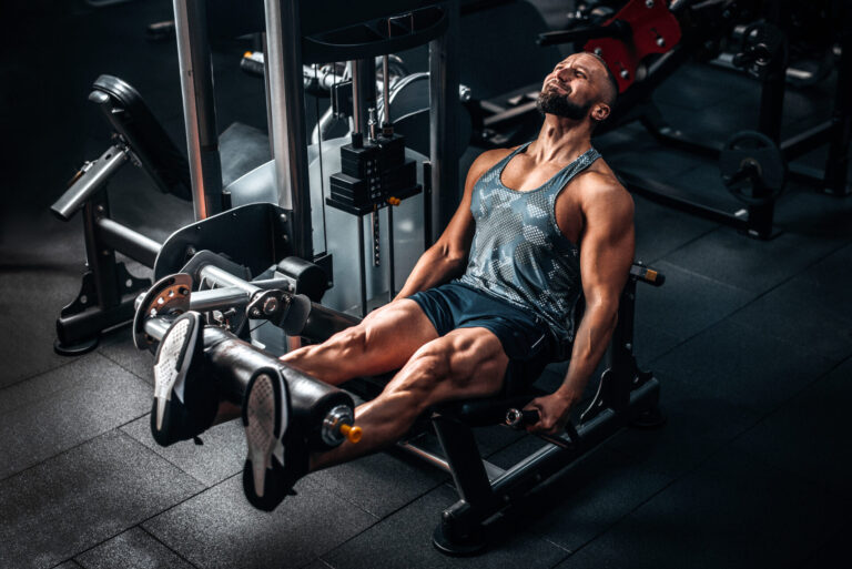 Sportler sind an der Beinstrecker Maschine und trainiert Oberschenkel. muscular,strength,caucasian,body,leg,fit,view,muscles,fitness,legs,club,press,day,sporty,active,equipment,weight,weights,focused,gym,bodybuilding,adult,athletic,male,full,concentrating,handsome,strong,exercise,training,exercising,lifting,muscle,indoors,working,hard,man,physical,tank,leisure,side,length,health,sportswear,blue,build,workout,healthy,machine,sport