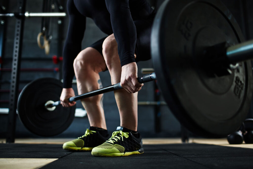Sport hebt eine Langhantel aus der tiefen Kniebeuge. sports-shoes, floor, human, sport, barbell, exercise, hand, young, cross-training, sportive, and 16 more